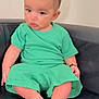 baby, black_couch, casual_wear, child, cute, expression, face, foot, green_clothing, indoor, infant, person, portrait, relaxed, seated, short_hair, sitting, skin, toes, young