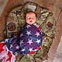 newborn, baby, flag, american_flag, camouflage, military_uniform, wooden_floor, sleeping, wrapped, infant, peaceful, portrait, person, flooring, fabric, indoor, closeup, resting, soft, symbolic
