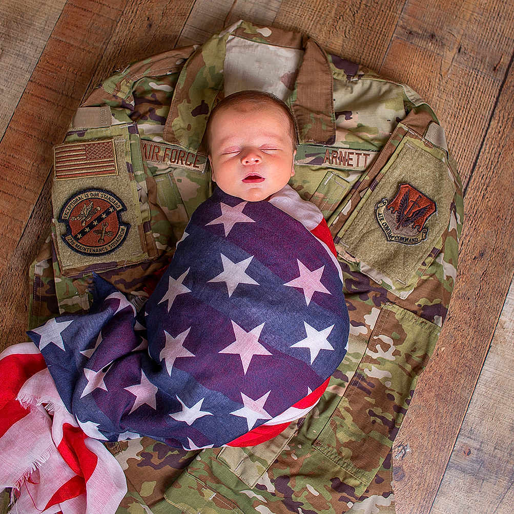 Cade joined the competition — help win amazing prizes! american_flag, baby, camouflage, closeup, fabric, flag, flooring, indoor, infant, military_uniform, newborn, peaceful, person, portrait, resting, sleeping, soft, symbolic, wooden_floor, wrapped