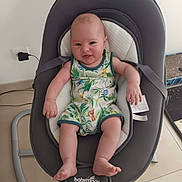 Aaron a rejoint le concours — aidez-le/la à gagner de superbes lots ! baby, infant, smiling, baby_rocker, romper, jungle_print, indoor, floor, power_outlet, modern_furniture, child, cute, happy, seated, legs, arms, head, face, skin, home
