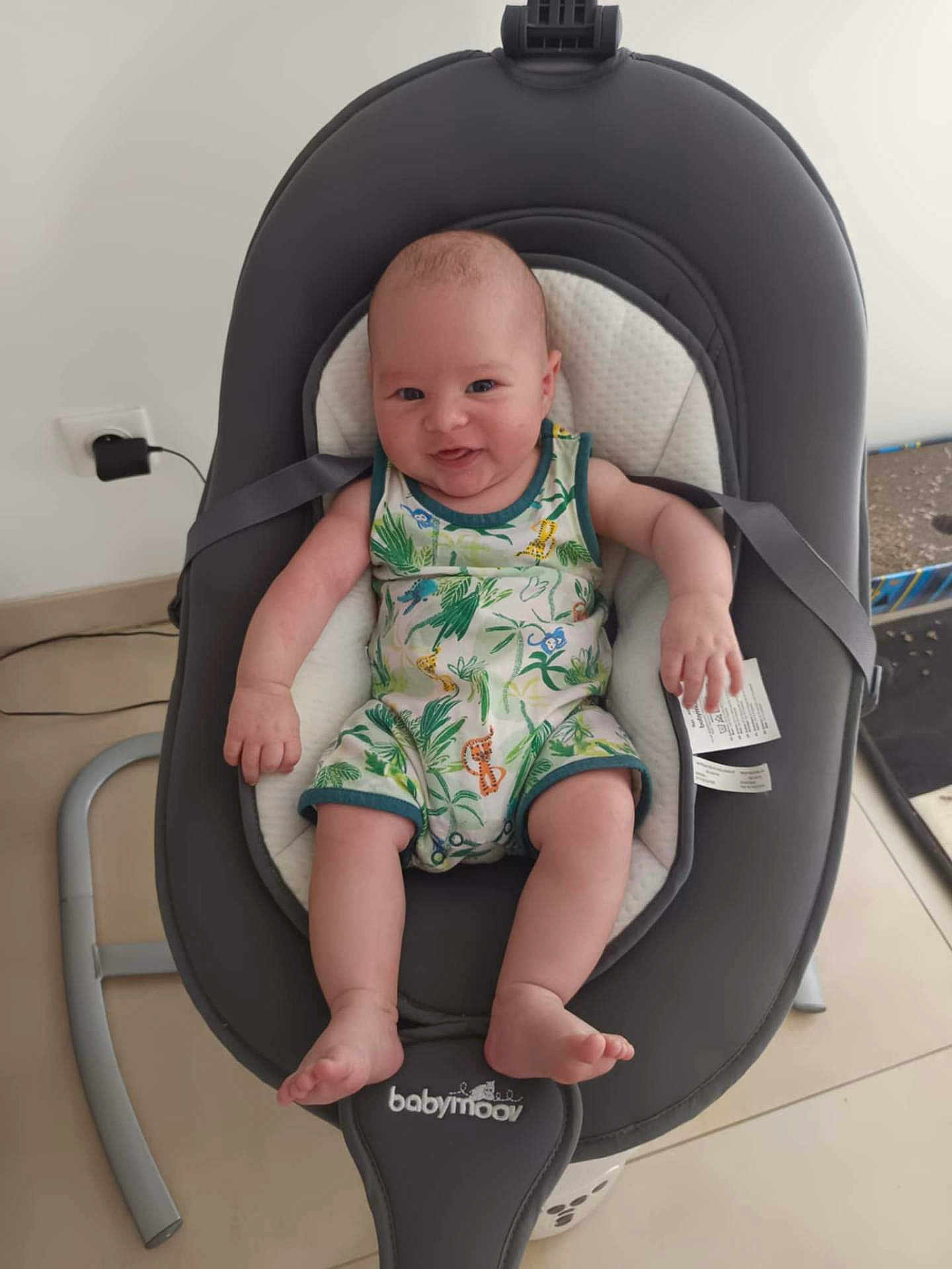 Aaron a rejoint le concours — aidez-le/la à gagner de superbes lots ! baby, infant, smiling, baby_rocker, romper, jungle_print, indoor, floor, power_outlet, modern_furniture, child, cute, happy, seated, legs, arms, head, face, skin, home