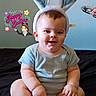 baby, bunny_ears, smiling, sitting, blue_shirt, cross_legged, black_surface, wall_decoration, hand, spoon, happy_easter_text, cute, indoor, child, portrait, headwear, infant, holiday, easter, playful