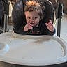 baby, toddler, child, high_chair, sitting, waving, smiling, curly_hair, brown_hair, face, hand, finger_food, food, crumbs, tray, kitchen, indoor, portrait, baby_gear, home