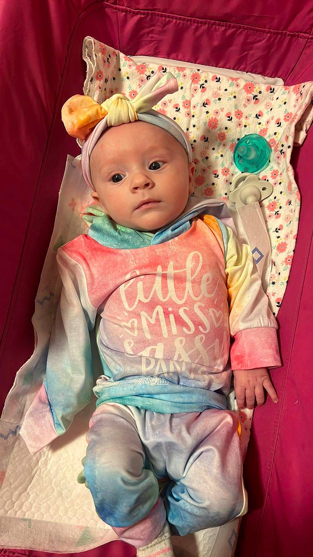 Elaine is registered to the contest to win money with this photo: baby, baby_products, baby_toddler_clothing, cheek, child, eye, face, fun, happy, head, headwear, human_body, linens, pattern, peach, person, pink, sitting, skin, sleeve