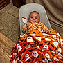 Emelia is registered to the contest to win money with this photo: baby, child, smiling, blanket, halloween, ghosts, bats, orange, baby_seat, carpet, floor, wood_floor, happy, cozy, indoors, clothing, person, cute, infant, portrait
