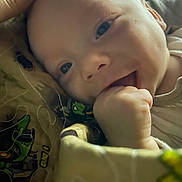 Carter joined the competition — help win amazing prizes! baby, infant, face, hand, smile, chewing, blanket, closeup, happy, cute, child, skin, eyes, cozy, person, indoors, soft_light, expression, newborn, resting