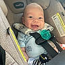 baby, car_seat, smile, pacifier, infant, happy, child, seatbelt, plush_toy, blue_clothing, straps, safety, cute, face, head, indoors, person, closeup, child_seat, sunlight