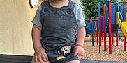 Jaziel joined the competition — help win amazing prizes! toddler, child, smiling, overalls, monkey_patch, sandals, wooden_railing, playground, play_structure, trees, outdoor, daylight, happy, person, short_sleeves, grass, blue_sky, wood_chips, fence, casual_clothing