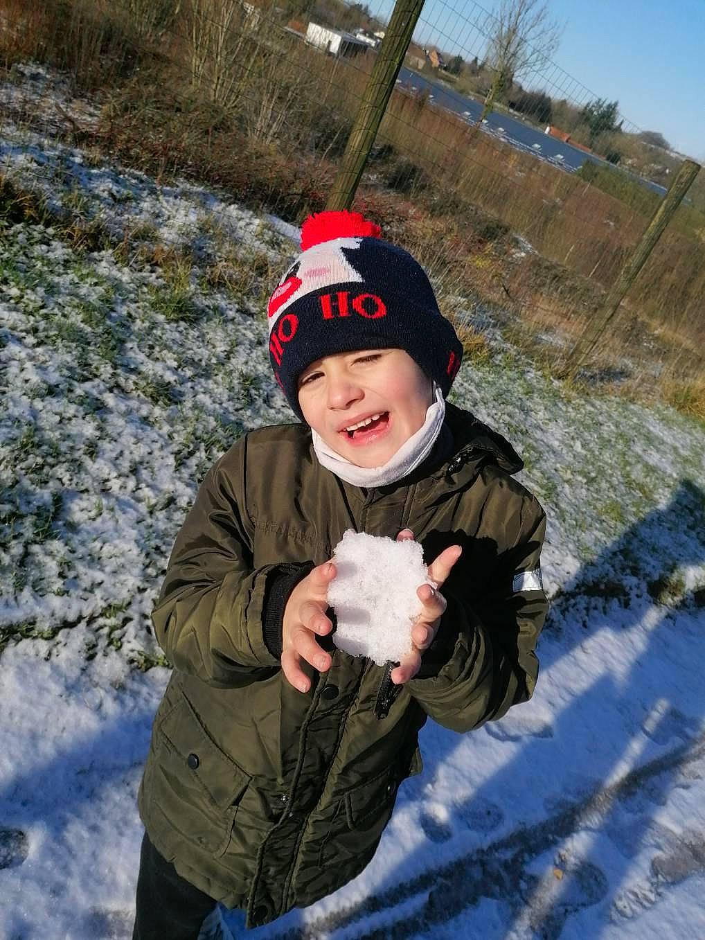 Lorenzo participe au concours pour gagner de l'argent avec cette photo : baseball_cap, cap, eye, face, flash_photography, freezing, fun, glove, grass, happy, head, headwear, jacket, person, plant, recreation, sky, smile, snow, toddler