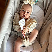 Ayline participe au concours pour gagner de l'argent avec cette photo : baby, infant, child, headband, bow, clothing, seat, baby_seat, soft_toys, hand, footwear, knitted_booties, card, curious, indoors, portrait, cute, expression, comfortable, caucasian_baby