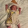 baby, infant, one_month, flag, overalls, giraffe, quilted_blanket, clothing, cute, milestone, lying_down, newborn, portrait, child, person, small_hands, small_feet, fabric, soft_lighting, indoor