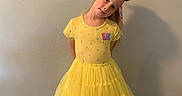 Venus is registered to the contest to win money with this photo: child, girl, yellow_dress, bow, posing, indoor, floor, wall, portrait, smile, long_hair, fashion, clothing, footwear, black_shoes, cute, standing, young, happy, casual