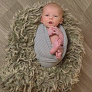 Jayden is registered to the contest to win money with this photo: baby, infant, swaddled, blanket, floor, wooden_floor, soft_texture, newborn, wrapped, cute, child, small, hands, feet, face, expression, portrait, indoor, cozy, fluffy