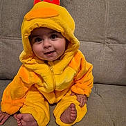 Ilyan a rejoint le concours — aidez-le/la à gagner de superbes lots ! baby, child, costume, duck, yellow, hood, couch, smile, cute, indoors, feet, hand, plush, sitting, face, person, apparel, cozy, infant, happy