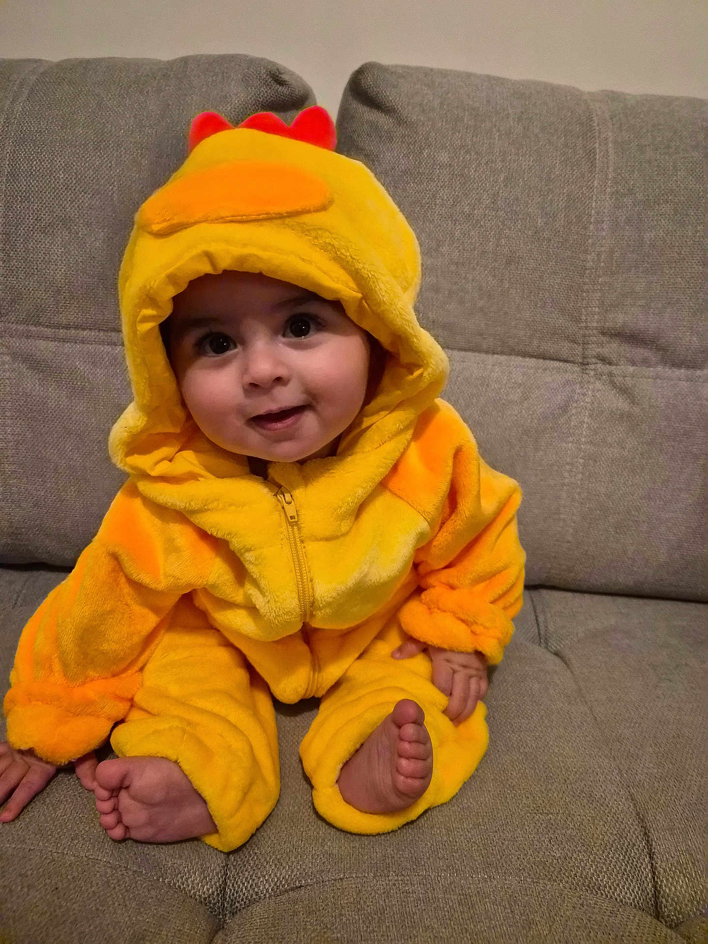 Ilyan a rejoint le concours — aidez-le/la à gagner de superbes lots ! baby, child, costume, duck, yellow, hood, couch, smile, cute, indoors, feet, hand, plush, sitting, face, person, apparel, cozy, infant, happy