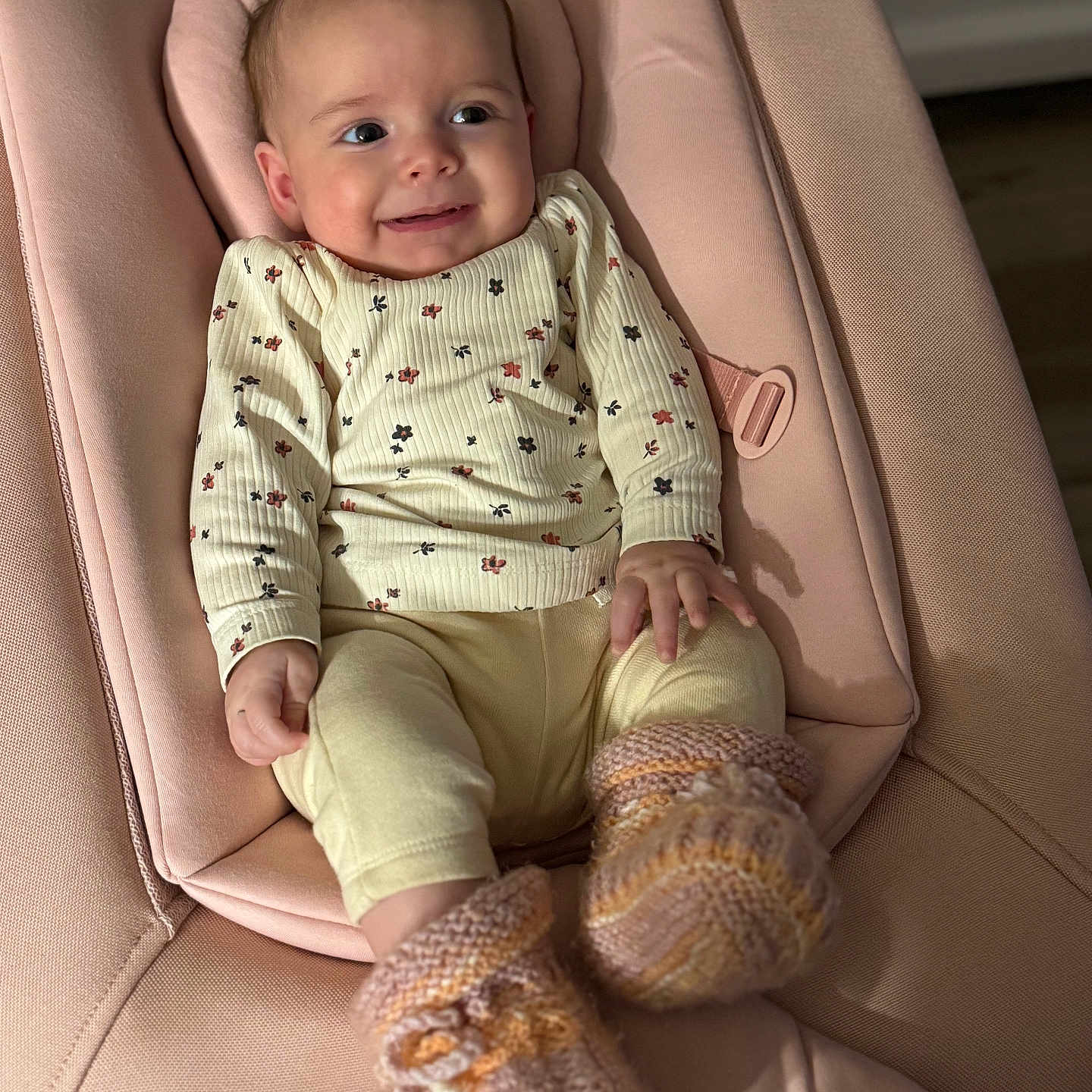 Mia participe au concours pour gagner de l'argent avec cette photo : apparel, baby, baby_girl, child, cozy, cute, floral_clothing, footwear, happy, indoors, infant, infant_clothing, knitted_booties, person, pink_cushion, portrait, seated, smile, soft_lighting, toddler
