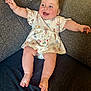 baby, child, smiling, happy, arms_outstretched, dress, bunny_pattern, couch, seated, indoor, rosy_cheeks, barefoot, infant, cute, plush, portrait, person, clothing, furniture, home