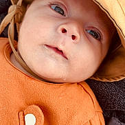 Timéo a rejoint le concours — aidez-le/la à gagner de superbes lots ! baby, infant, face, hat, orange_clothing, closeup, child, cute, eyes, skin, expression, newborn, portrait, headwear, apparel, person, young, soft_texture, warm_colors, cozy