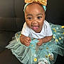 baby, child, tutu, headband, golden_bow, blue_tutu, polka_dots, smiling, happy, sitting, black_couch, white_shirt, sandals, cute, indoors, portrait, toddler, fashion, playful, face