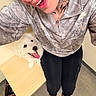 black_pants, canine, cute, dog, floor, friendly, happy, indoor, jacket, light, looking_up, person, pet, playing, selfie, smiling, table, tattoo, tongue_out, white_dog