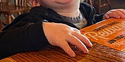 Noah joined the competition — help win amazing prizes! toddler, child, smiling, happy, restaurant, menu, wooden_table, indoor, person, clothing, face, hand, furniture, chair, cozy, casual, portrait, light, background, messy_face