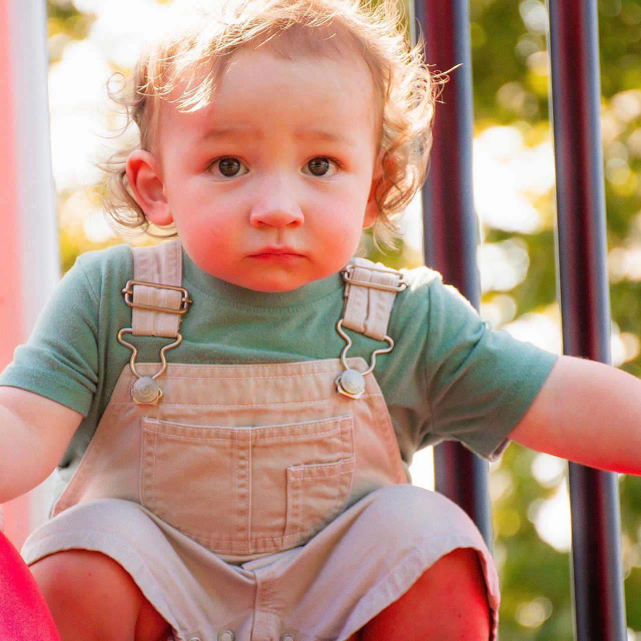 Noah joined the competition — help win amazing prizes! candid, child, curly_hair, daylight, expression, eyes, face, green_shirt, legs, nature, outdoor, overalls, park, person, playground, shoes, slide, summer, toddler, young_child