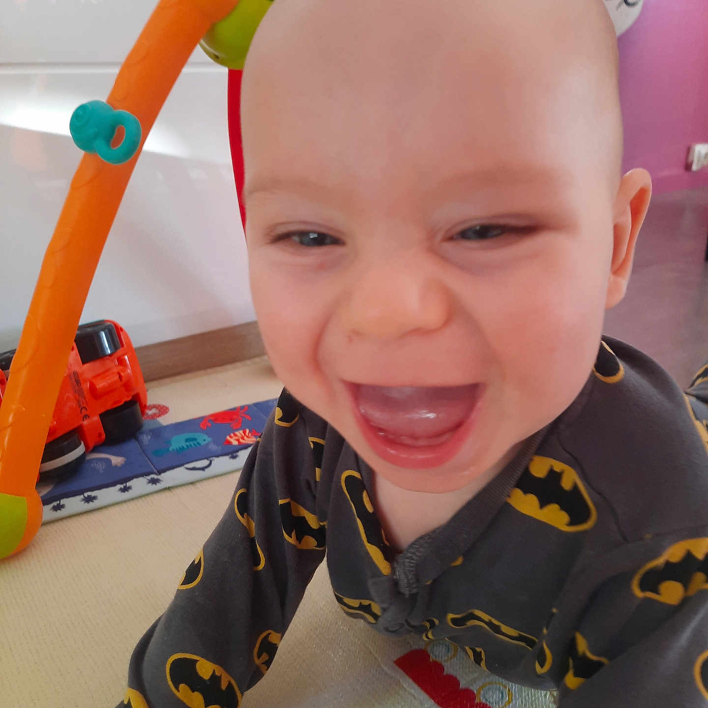 Rafael a rejoint le concours — aidez-le/la à gagner de superbes lots ! baby, batman, child, clothing, crawling, expression, face, floor, happy, head, home, indoor, infant, laughing, mouth_open, onesie, person, play_gym, smiling, toy