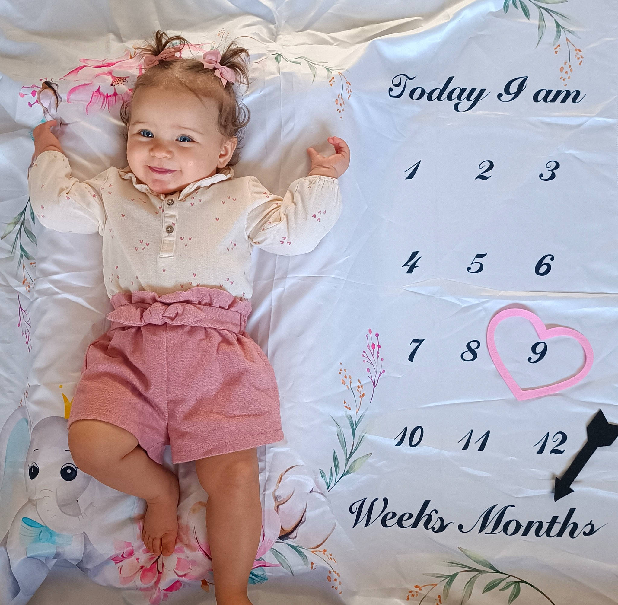 Leïa a rejoint le concours — aidez-le/la à gagner de superbes lots ! baby_toddler_clothing, facial_expression, finger, font, happy, human_leg, joy, knee, magenta, pattern, person, pink, shorts, skin, sleeve, smile, sock, textile, thigh, toddler