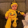 Reggie joined the competition — help win amazing prizes! baby, blanket, child, couch, cozy, cute, duck_print, expression, furniture, hat, indoor, infant, onesie, person, portrait, sitting, soft_texture, warm, yellow_clothing, young