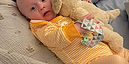 Reggie is registered to the contest to win money with this photo: baby, bed, blanket, child, comfort, cute, fabric, face, home, indoor, infant, onesie, person, pillow, portrait, resting, sleepwear, soft_toy, stuffed_animal, toy