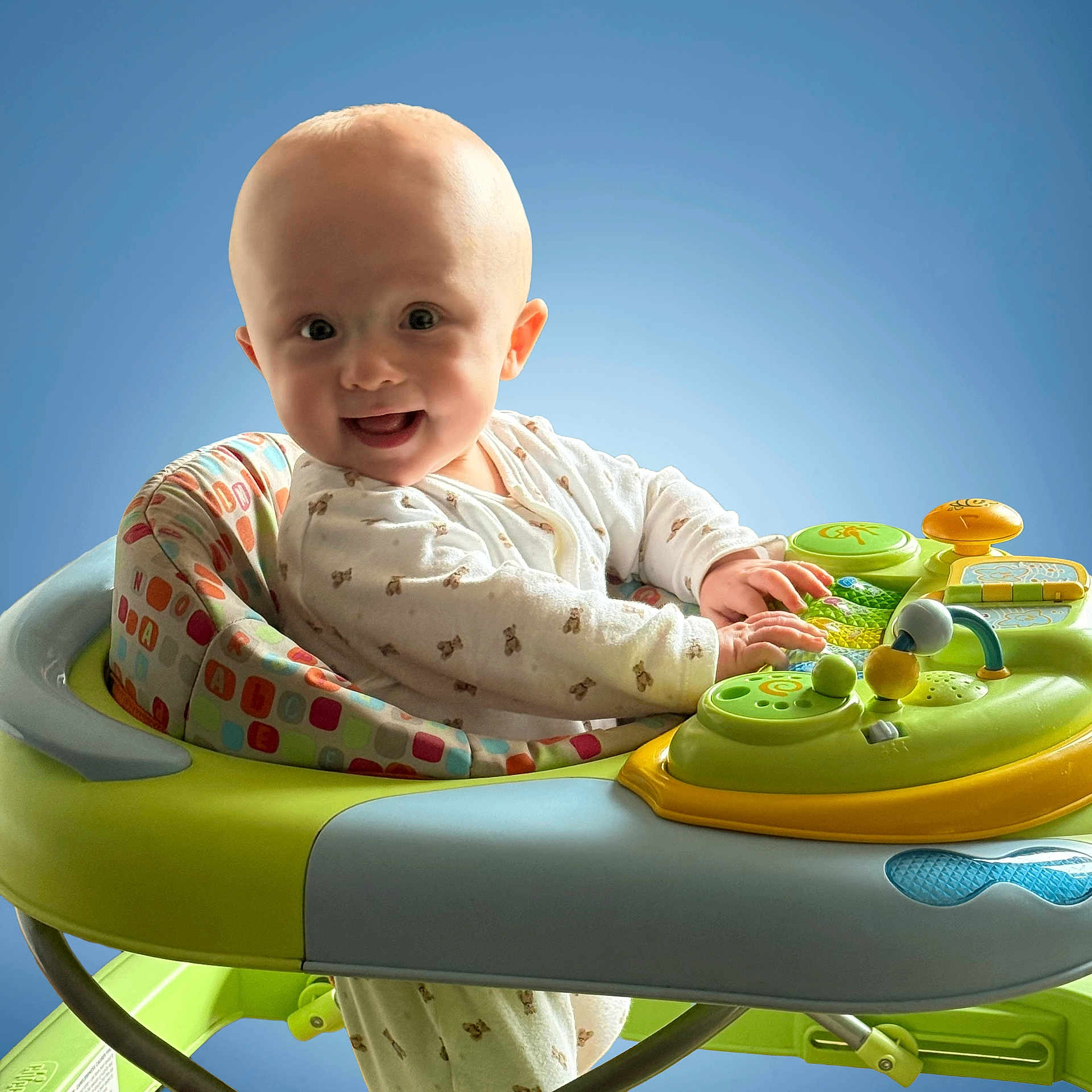 Reggie is registered to the contest to win money with this photo: baby, background, bright, child, clothing, colorful, cute, expression, face, hands, happy, head, indoor, infant, play, seat, smiling, toy, walker, young