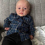 Reggie joined the competition — help win amazing prizes! baby, black_pants, blanket, blue_shirt, casual, child, clothing, couch, expression, face, home, indoor, infant, looking_at_camera, person, plaid_shirt, portrait, seated, soft_lighting, young_child