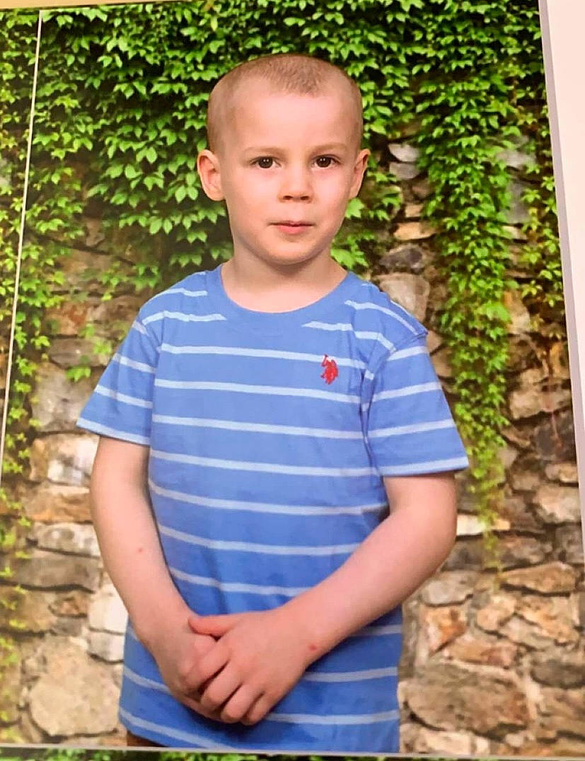 Bradley is registered to the contest to win money with this photo: baby_toddler_clothing, chin, electric_blue, eye, face, forehead, fun, grass, hair, hairstyle, happy, head, orange, pattern, people_in_nature, person, plant, sleeve, standing, t_shirt