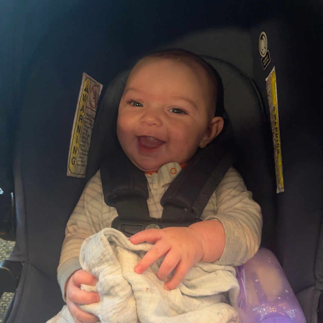 Colton is registered to the contest to win money with this photo: baby, babylaughing, bed, blanket, bodypart, bottle, clothing, face, finger, furniture, hand, happy, head, pants, person, photography, portrait, smile, stroller, waterbottle