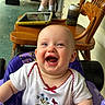 baby, child, smiling, happy, indoor, chair, wooden_chair, tablet, can, koozie, porch, clothing, white_shirt, floral_embroidery, person, legs, socks, toy, activity_chair, closeup