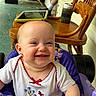 baby, smiling, child, purple_baby_walker, white_shirt, embroidery, red_bow, wooden_chair, tablet, drink_can, porch, green_floor, person, socks, shoes, door, hand, face, happy, indoor