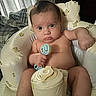 baby, infant, toy, rattle, seat, cushion, teddy_bear_print, indoor, child, person, skin, expression, serious, hand, face, head, legs, comfort, furniture, curtains