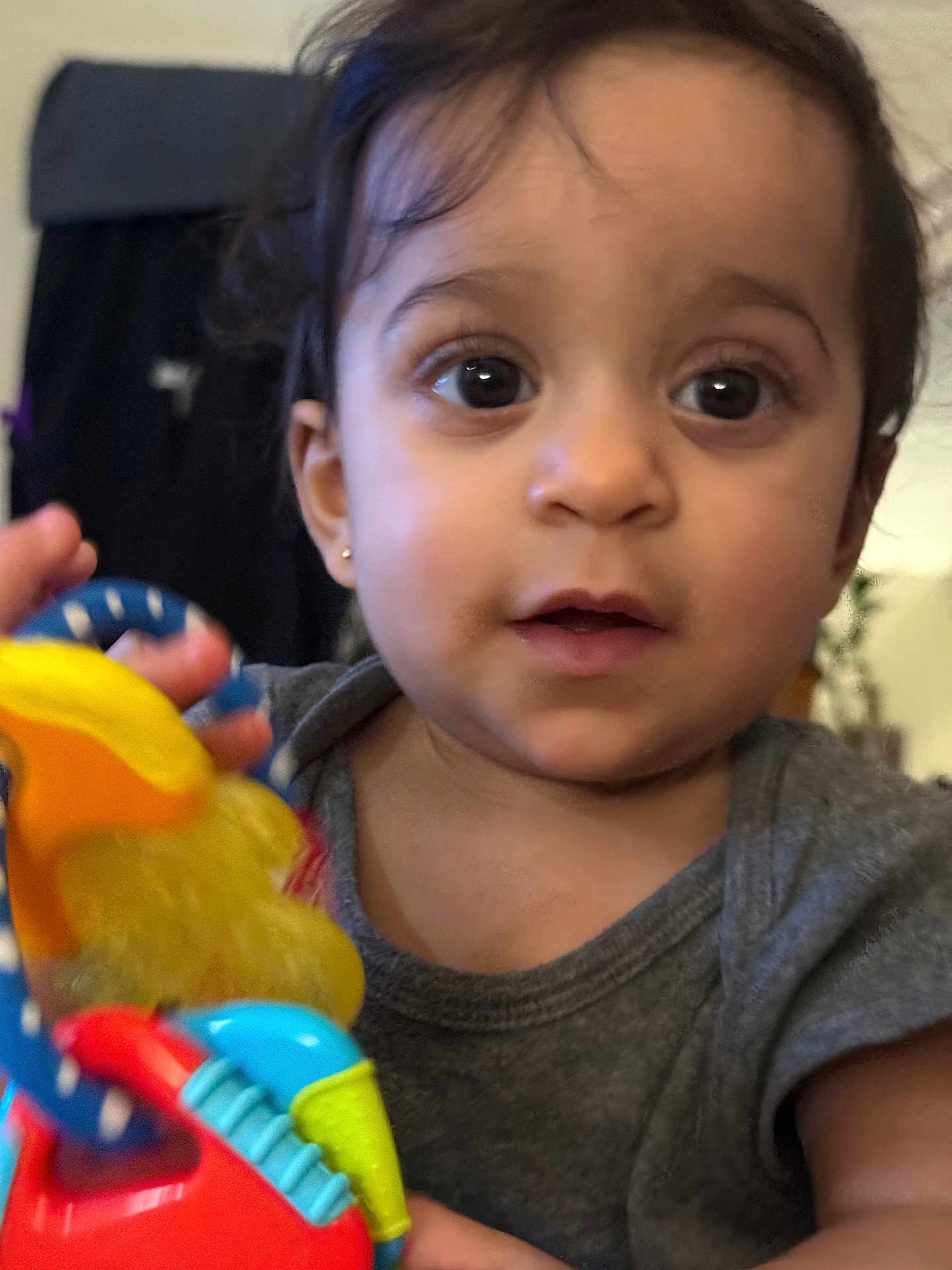Kathalina is registered to the contest to win money with this photo: toddler, child, toy, colorful, face, eyes, curly_hair, earring, shirt, indoor, person, portrait, cute, young_child, baby, hand, expression, skin, focus, closeup