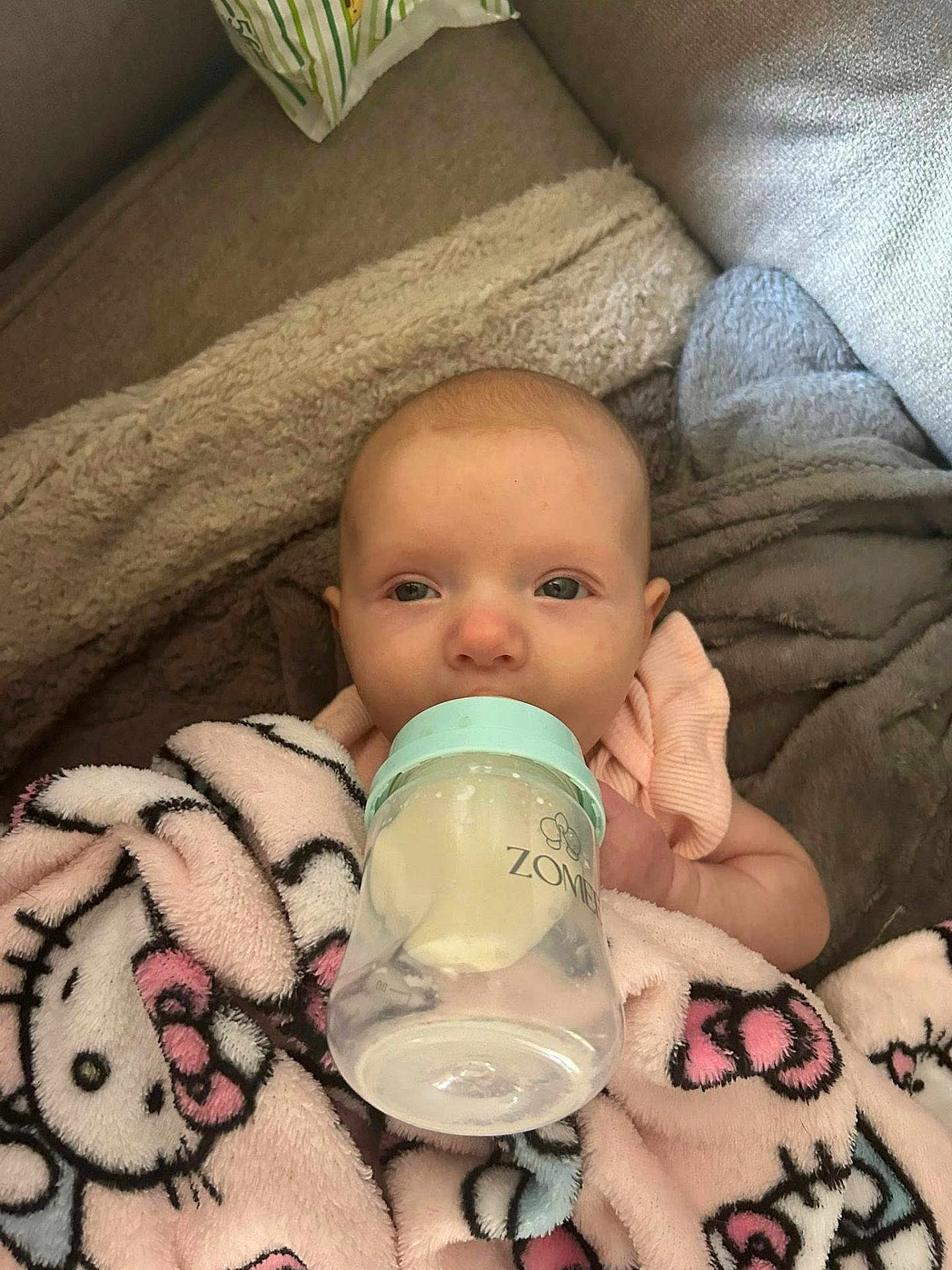 Alara is registered to the contest to win money with this photo: baby, bottle, blanket, hello_kitty, child, infant, feeding, couch, soft, comfort, indoors, cute, face, wrapped, pink, relaxed, young, person, nursing, cozy