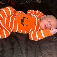 Alara joined the competition — help win amazing prizes! baby, sleeping, infant, onesie, orange, white_stripes, jack_o_lantern, cozy, blanket, bed, resting, cute, child, newborn, person, face, hand, mouth, nose, ear