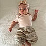 Margot is registered to the contest to win money with this photo: baby, infant, headband, bow, striped_pants, beige_clothing, lying_down, blanket, cute, child, portrait, indoors, soft_lighting, expression, small_hands, foot, looking_up, human, one_person, fashion