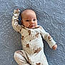 baby, infant, onesie, bear_print, quilt, textured_bedspread, lying_down, cute, smiling, child, sleepwear, bedroom, soft_lighting, portrait, happy, small_person, cozy, face, hand, foot