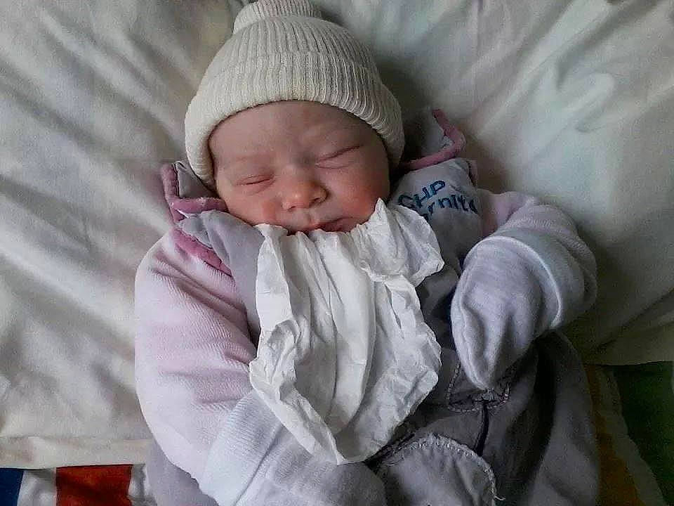 Kaëlla a rejoint le concours — aidez-le/la à gagner de superbes lots ! baby, baby_products, baby_safety, baby_sleeping, baby_toddler_clothing, beanie, cap, cheek, child, comfort, headwear, knit_cap, linens, nap, person, sleep, smile, textile, thumb, toddler