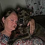 Greyson is registered to the contest to win money with this photo: woman, dog, indoor, portrait, brindle_dog, couch, floral_curtains, closeup, serious_expression, human, pet, animal, affection, casual_clothing, adult, holding, companion, home, relaxed, friendship