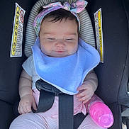 Sofia is registered to the contest to win money with this photo: baby, car_seat, headband, bib, bottle, pink, straps, infant, child, seatbelt, clothing, cute, portrait, sitting, hand, face, expression, indoors, safety, rest