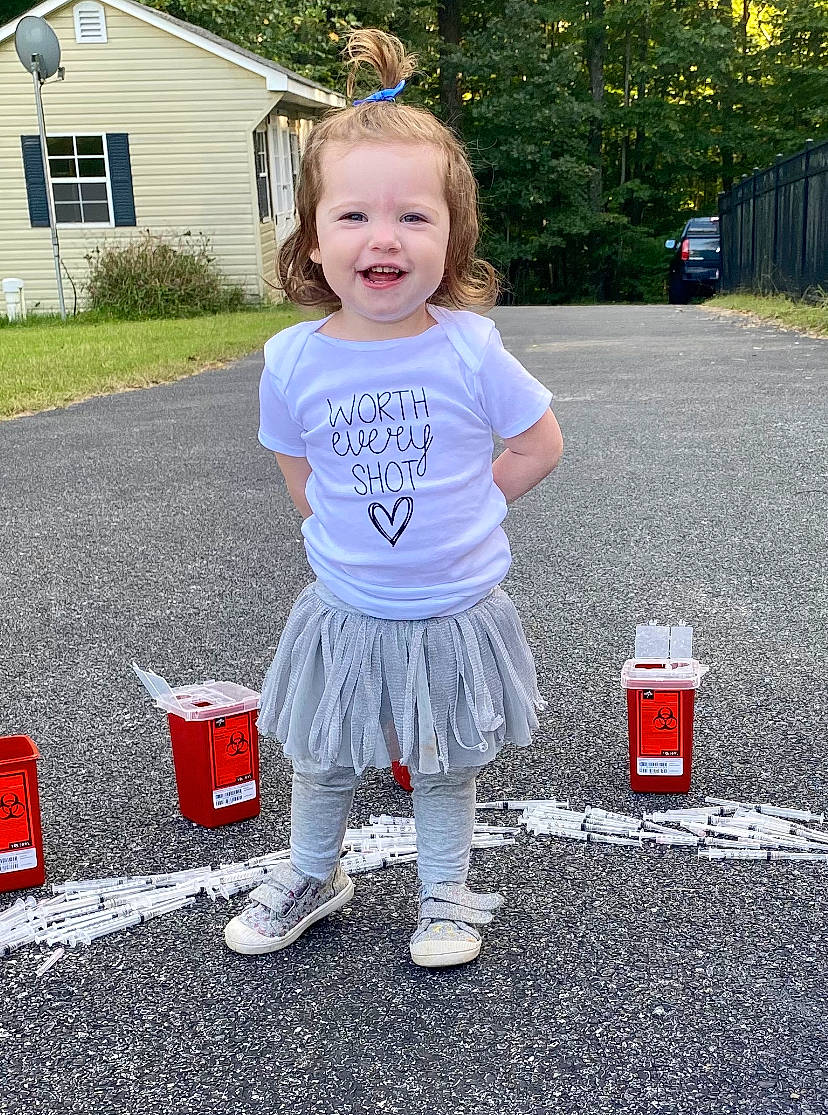 Brooklynn is registered to the contest to win money with this photo: asphalt, baby_toddler_clothing, eye, face, fun, grass, hair, happy, head, joy, person, pink, plant, public_space, road_surface, sleeve, smile, standing, toddler, tree