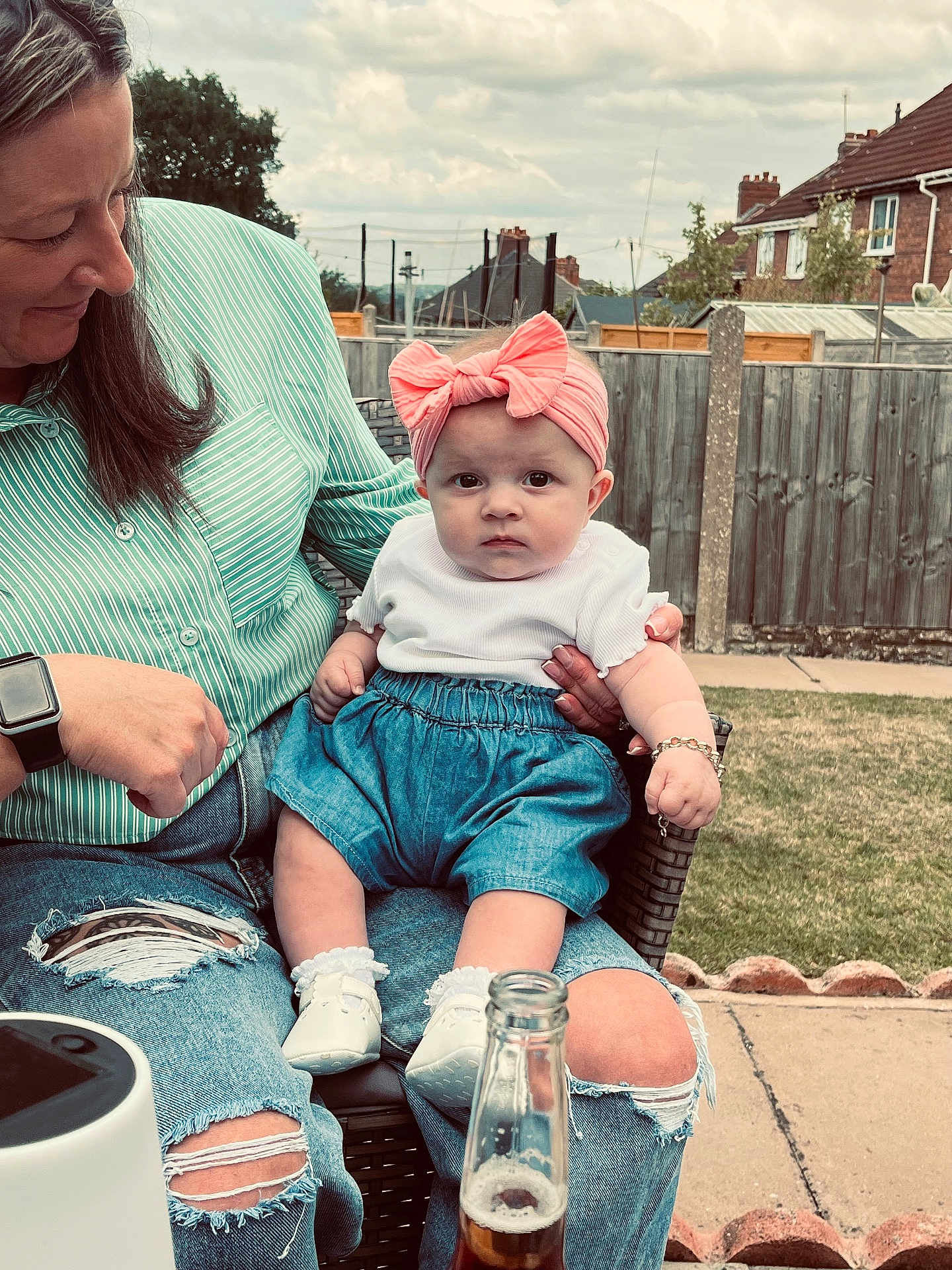 Phoebe is registered to the contest to win money with this photo: baby, child, adult, woman, outdoor, garden, grass, fence, clothing, headband, denim, shoes, bottle, person, jeans, ripped_jeans, sitting, portrait, sky, casual