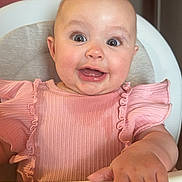 Yazmin joined the competition — help win amazing prizes! baby, child, high_chair, pink_clothing, smile, happy, cute, indoor, person, face, hand, skin, portrait, infant, young_child, apparel, seat, furniture, expression, human