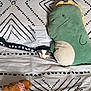 bed, black, blanket, brown, cat, cozy, curious, cute, dinosaur_plush, eyes, fabric, green, indoor, pattern, peeking, plush_toy, resting, soft_toy, teddy_bear, white