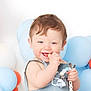 baby, child, smiling, blue_eyes, brown_hair, balloons, pastel_colors, toy, beads, hand, face, clothing, infant, cute, happy, portrait, indoor, celebration, festive, cheerful